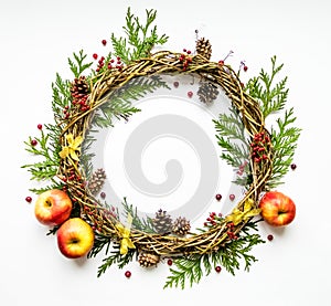 Festive wreath of vines with apples, thuja branches, rowanberries and cones. Flat lay, top view