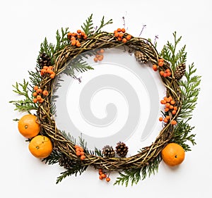 Festive wreath of vines with tangerines, thuja branches, rowanberries and cones. Flat lay, top view