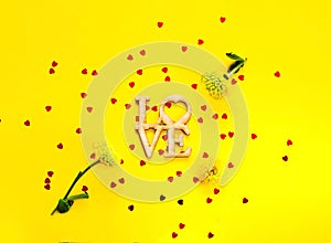 Festive yellow background with spangles in the shape of heart. Concept Valentines Day or Mothers Day.