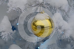Festive yellow ball on a white Christmas tree