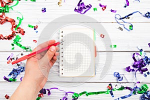 Festivedecorations and notebook with wish list on white rustic table, flat lay style. Planning concept.- Image