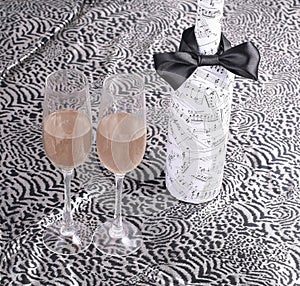 Festively decorated bottle of wine and two glasses on lace tabl