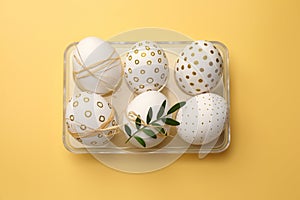 Festively decorated chicken eggs on yellow background, top view. Happy Easter