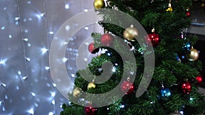 Festively decorated Christmas tree stands in a room with luminous garlands