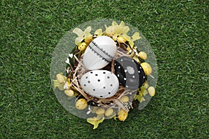 Festively decorated Easter eggs on green grass, top view