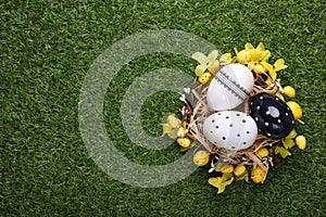 Festively decorated Easter eggs on green grass, top view. Space for text