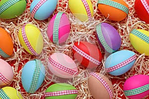 Festively decorated Easter eggs in paper filler on red background, flat lay