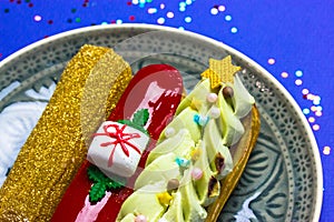 Festively decorated eclairs in New Year's style 2022 lying on round gray plate.