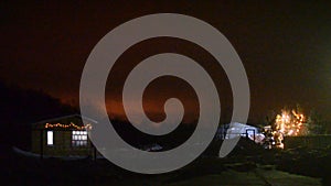 Festively decorated village plot with a house and Christmas trees with garlands in the snow on new year`s