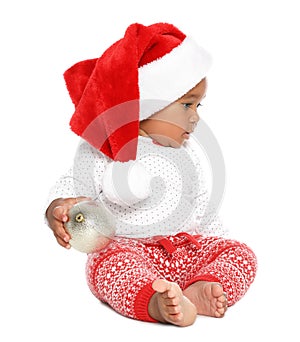 Festively dressed African-American baby with Christmas ball on background