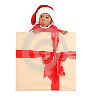 Festively dressed African-American baby in Christmas gift box on background