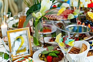 Festively served table with different food, decorated with flowers for banquet, restaurant interior