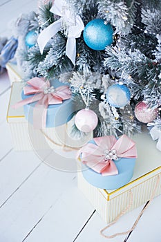 Festively wrapped gifts in pastel colors under decorated snowy Christmas tree