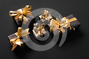 Festively wrapped golden gift boxes on black background. Isometric view. Holiday and black friday concept