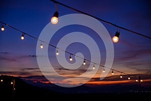 Festoon string lights decoration at the party event festival against sunset sky. light bulbs on string wire with copy space.