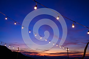 Festoon string lights decoration at the party event festival against sunset sky. light bulbs on string wire with copy space.
