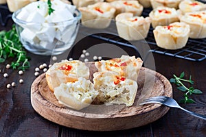 Feta cheese and fried onion mini quiche muffins, on wooden plate and cooling rack, horizontal