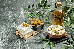 Feta cheese with olives and green herbs and olive oil sauce in bowl on dark background. place for text, top view
