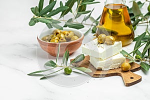 Feta cheese with olives and green herbs and olive oil sauce in bowl on light background. place for text, top view