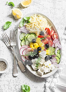 Feta, orzo, tomatoes, cucumbers, radishes, olives, peppers salad on a light background, top view. Healthy food concept. Mediterran