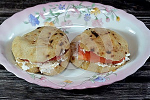 Feta white cheese with slices of tomatoes inside a mini traditional Egyptian flat bread with wheat bran and flour, small Aish