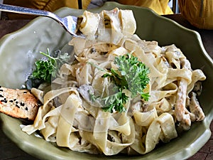 Fettuccine Alfredo Pasta Dish with Cream, Chicken and Parsley served at Restaurant.