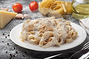 Fettuccine with cheese on a white plate and on a dark background.