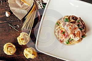 Fettuccine pasta with chicken breast and mushroom composition at dark wooden background