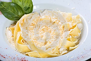 Fettuccine pasta with parmesan cheese, basil and cream sauce on dark wooden background
