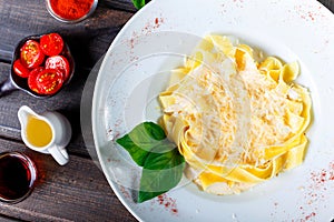 Fettuccine pasta with parmesan cheese, basil and cream sauce on dark wooden background