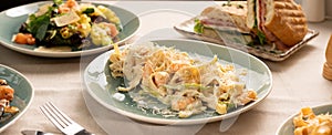 Fettuccine pasta with shrimp in a creamy sauce with cheese served on a plate on the table with other dishes for dinner