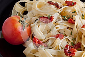 Fettuccine pasta with sun-dried tomatoes and various herbs. Close up