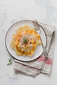 Fettuccine pasta with traditional Italian Passat sauce and parmesan cheese in light plate on old white concrete background.