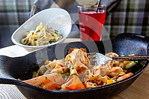 Fettuccine pasta with vegetables in a cast-iron frying pan