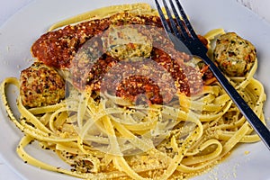 Fettuccine top with sauce and chicken meatball on a blue plate