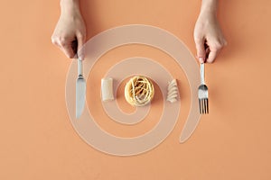 Fettuccine, tortiglioni, fusilli pasta and hands with fork and knife, concept photography for food blog or advertising