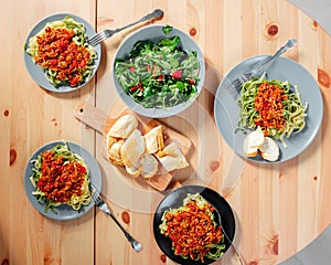 Fetuchini pasta with beef tomato sauce on wood table , italian food. Fresh salad in a gray plate with arugula