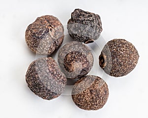 Few allspice jamaica peppercorns close up on gray