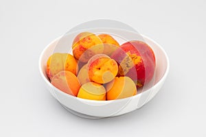 Few biologic nectarina, apricots on white bowl