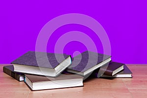 A few books on wooden deck table and soft purple background