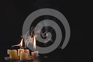 A few Candles isolated over dark background. Used, almost extinguished. Burned out. Copy space. Mystical smoke swirls in the