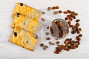 Few cookies with raisin and bowl with dried grape, scattered raisin on wooden table. Top view