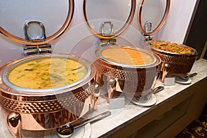 A few dishes of Paneer Makhani and mixed vegetables on heating pots kept warm