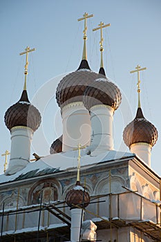 Few domes with crosses over a white-stone temple against a blue sky