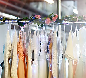 Few elegant wedding, bridesmaid ,evening, ball gown or prom dresses on a hanger in a bridal shop