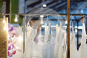 Few elegant wedding, bridesmaid ,evening, ball gown or prom dresses on a hanger in a bridal shop