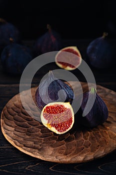 A few figs on a plate on an black wooden background