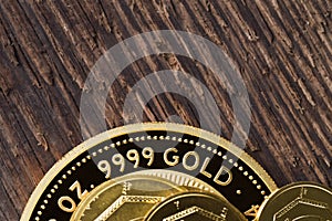 A few gold coins fineness 999.9 on a background of rough wood texture
