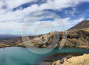 A few hikers on the banks of one of the Emerald Lakes high up on the Tongariro alpine crossing