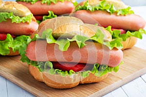 A few hot dogs on a wooden Board. Hot dog with lettuce tomato and sausage. Copy space.